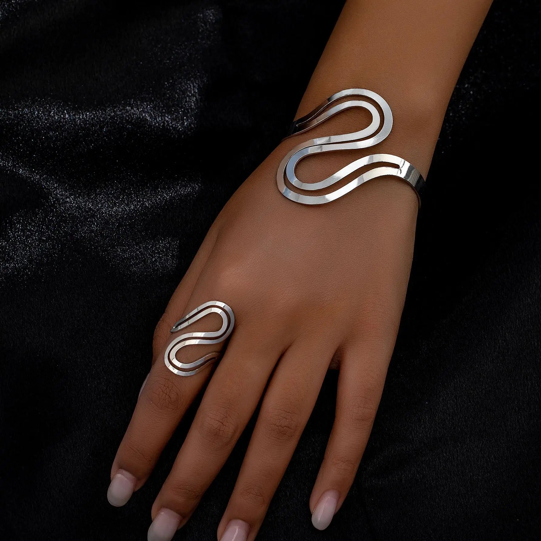 Close-up of a hand wearing a silver snake wave bracelet and ring set, featuring a sleek minimalist design