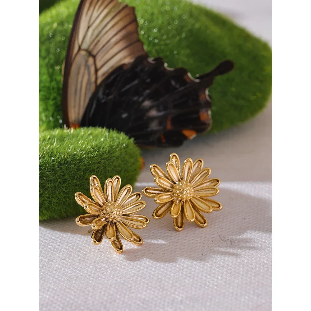 Gold flower stud earrings displayed on a natural setting with a butterfly, highlighting their intricate stainless steel design. Stylish button stud earrings for women.