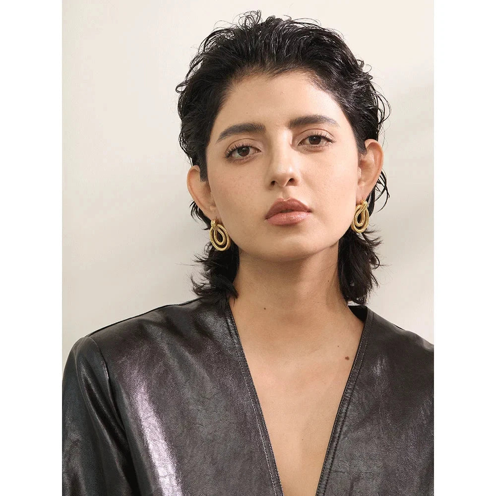 Model wearing stainless steel geometric snake earrings in gold-tone. A bold and stylish accessory for women’s fashion.