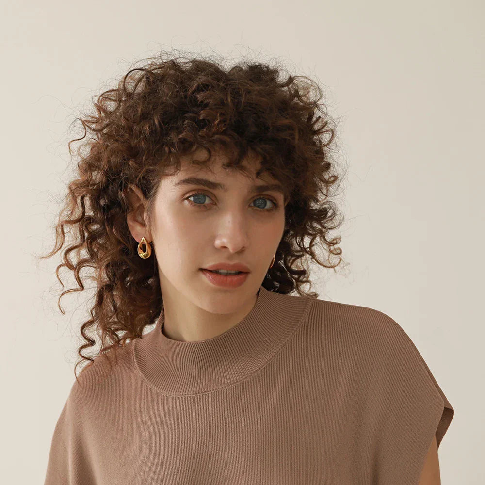 Model wearing gold stainless steel round hollow stud earrings. Stylish and vintage-inspired jewelry piece for women’s everyday wear.