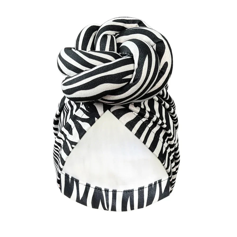 Black and white zebra-striped patterned knot turban headwrap, offering a bold and fashionable headwear option.
