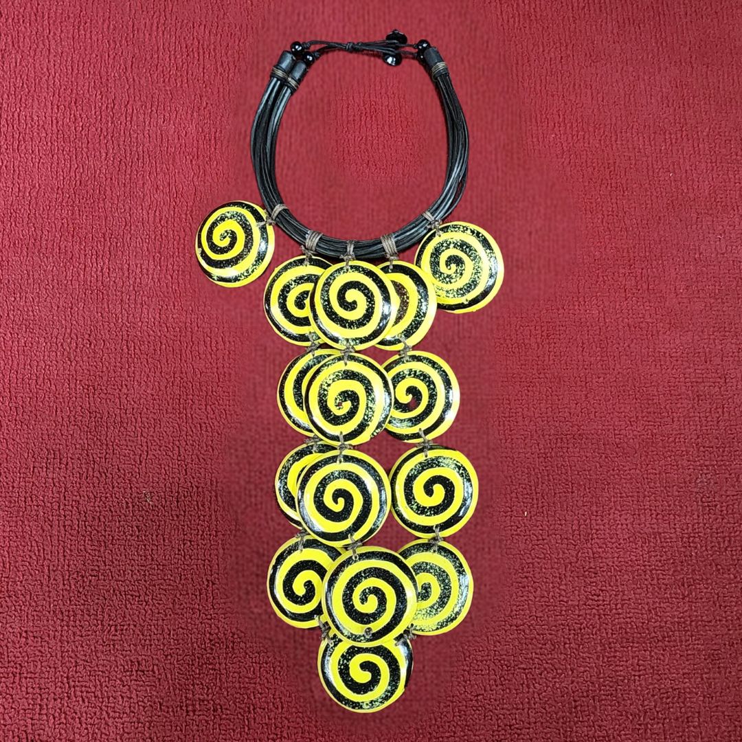 Sunny Swirls Cascade Necklace featuring bold yellow and black spiral wooden beads on a multi-strand black cord. Handmade statement jewelry piece.
