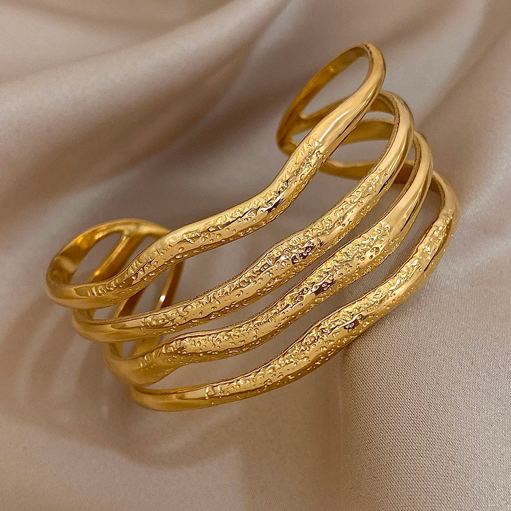 Close-up of a gold cuff bracelet featuring textured wavy layered bands, shown with measurement lines