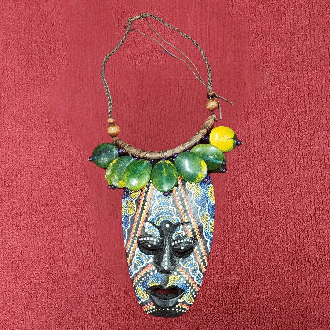Verdant Mystique Mask Necklace featuring a handcrafted African-inspired wooden pendant with intricate beadwork and green stone accents. A unique statement piece for cultural and artistic jewelry lovers.