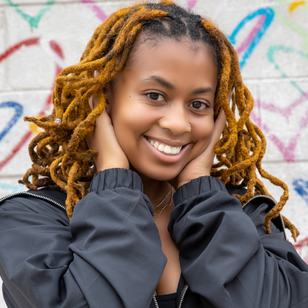 Smiling woman with golden brown human hair loc extensions styled in a curly look. The 0.6 cm thick locs offer a natural and stylish appearance.
