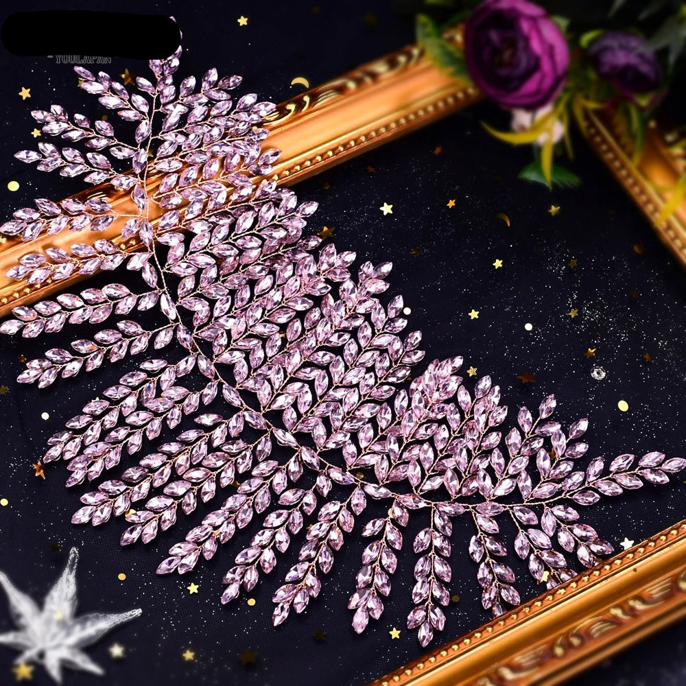 Top view of pink leaf bridal tiara with crystal detailing on black starry background.