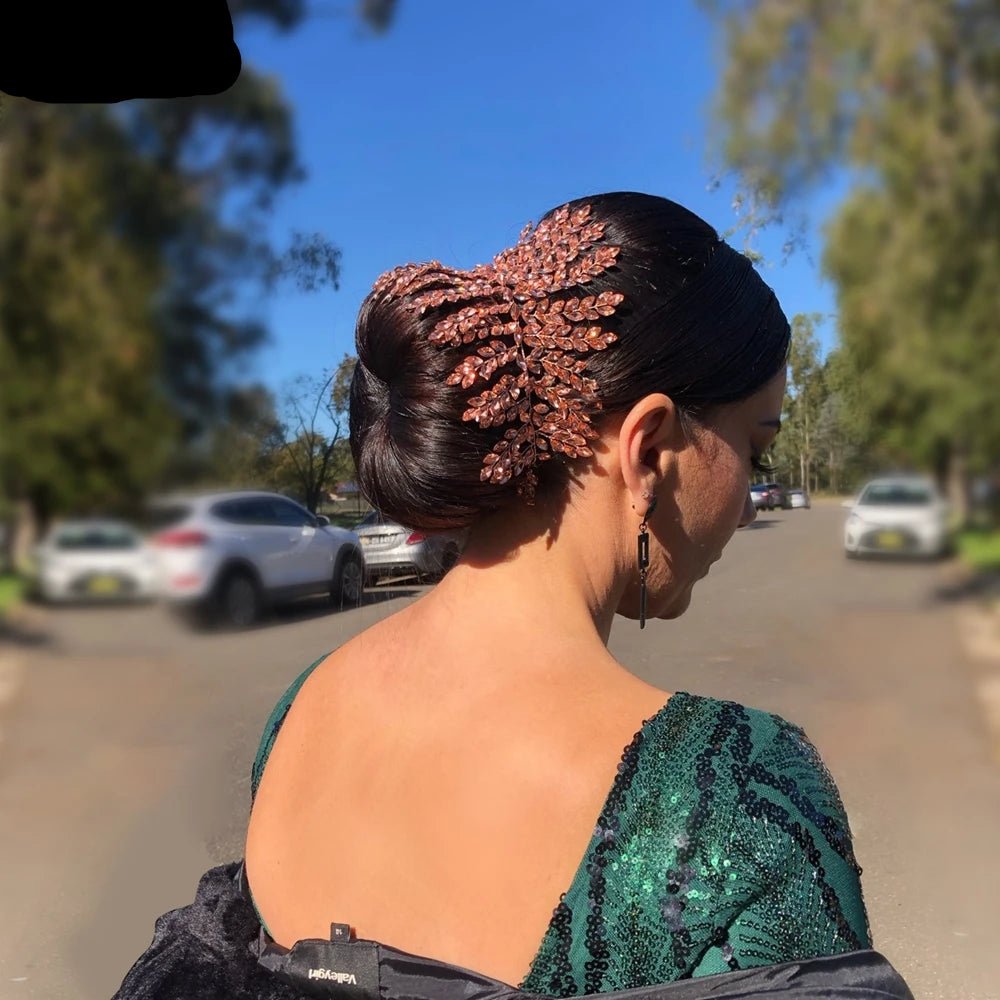 Bride wearing rose gold leaf tiara on sleek bun hairstyle outdoors