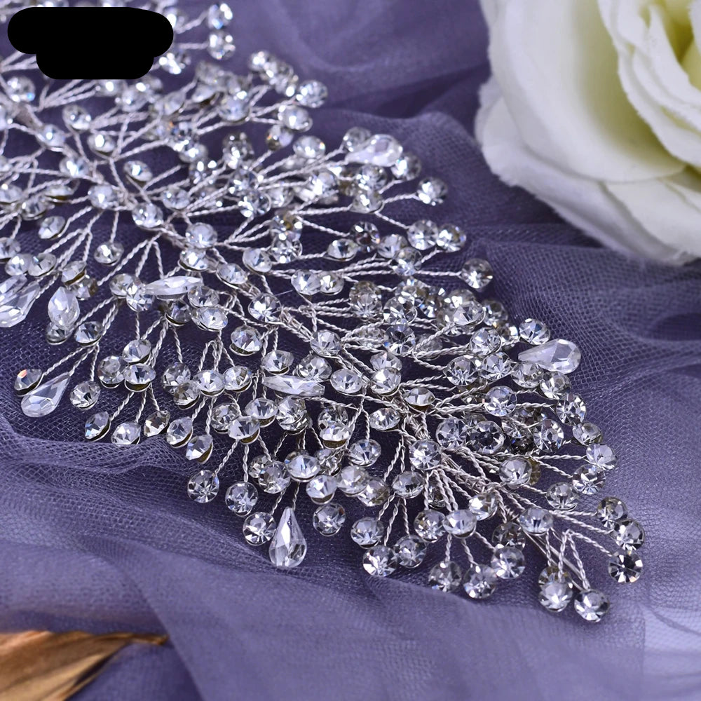 Close-up of silver bridal tiara with teardrop and round-cut crystals arranged in delicate branch design