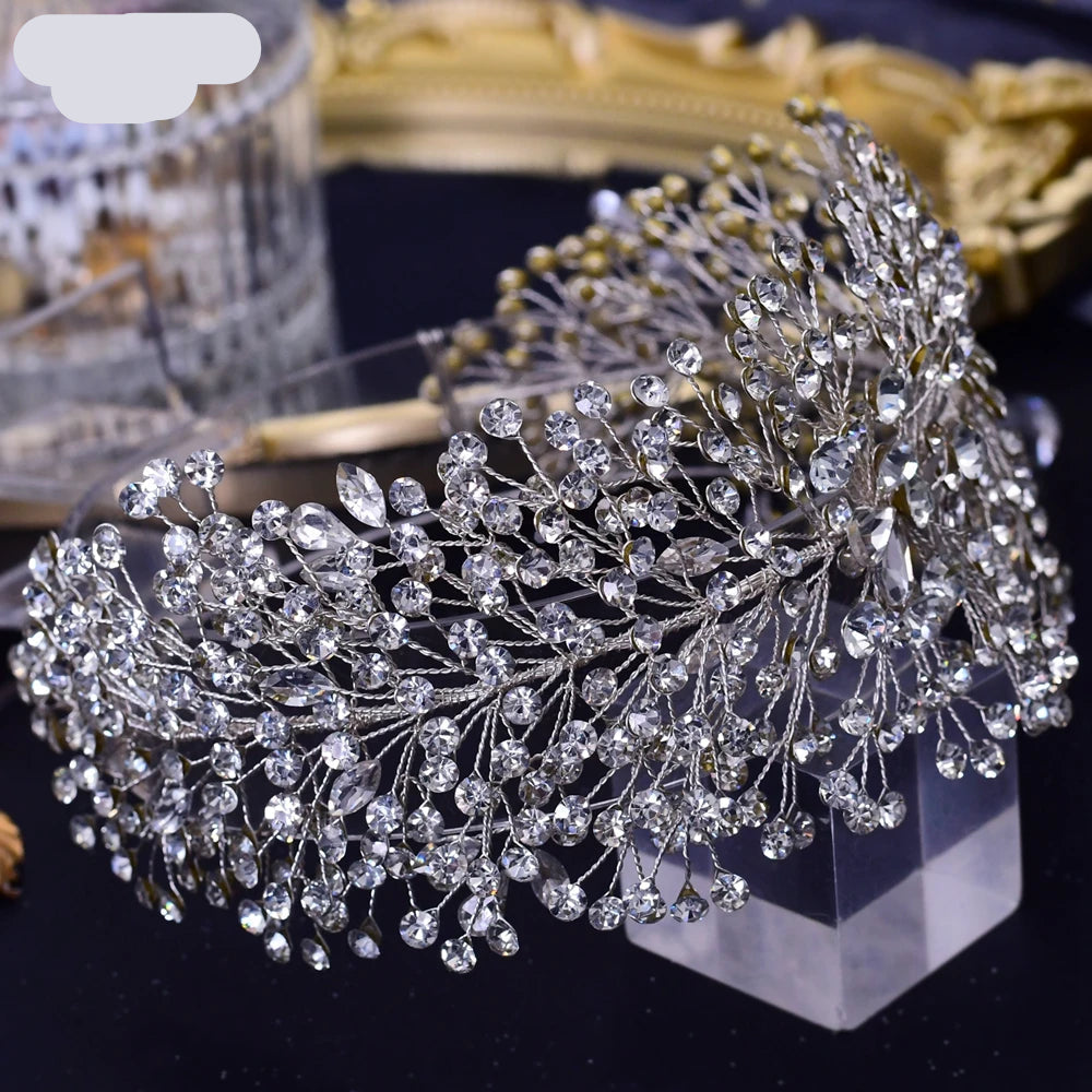 Silver bridal tiara with shimmering crystal branches styled on clear display stand with soft lighting