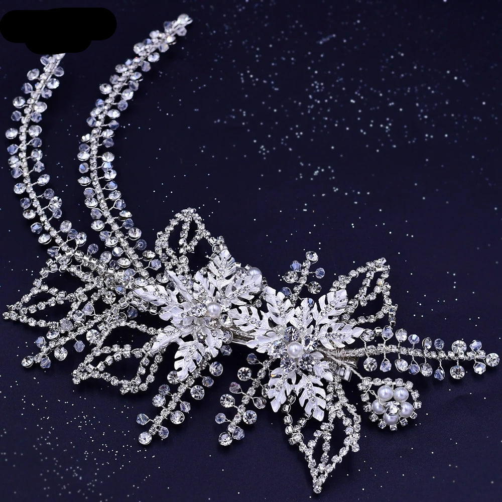 Silver bridal tiara with crystal leaves, pearl accents, and curved vine details displayed on black background