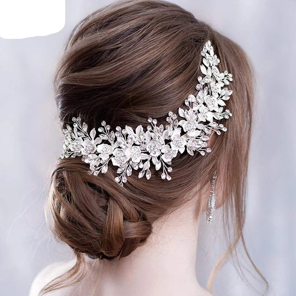 Bride wearing silver floral rhinestone headpiece wrapped elegantly around low bun hairstyle.