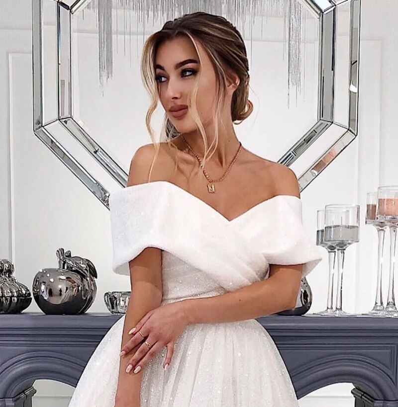 Close-up of ivory off shoulder glitter wedding dress showing detailed neckline and sparkle, perfect for beach bridal looks.
