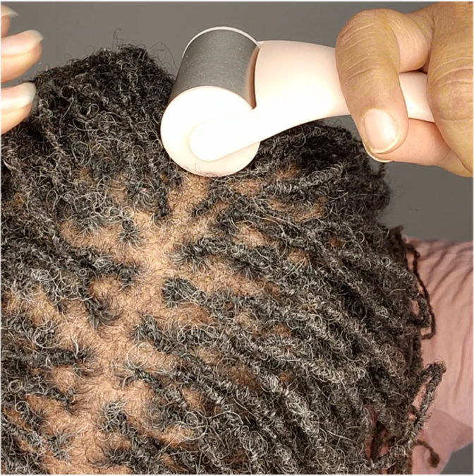 Woman using a cryotherapy scalp roller to ease scalp irritation and promote healthy loc maintenance.