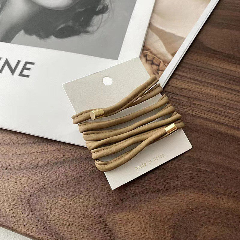 Set of beige hair ties on a white card with a blurred background