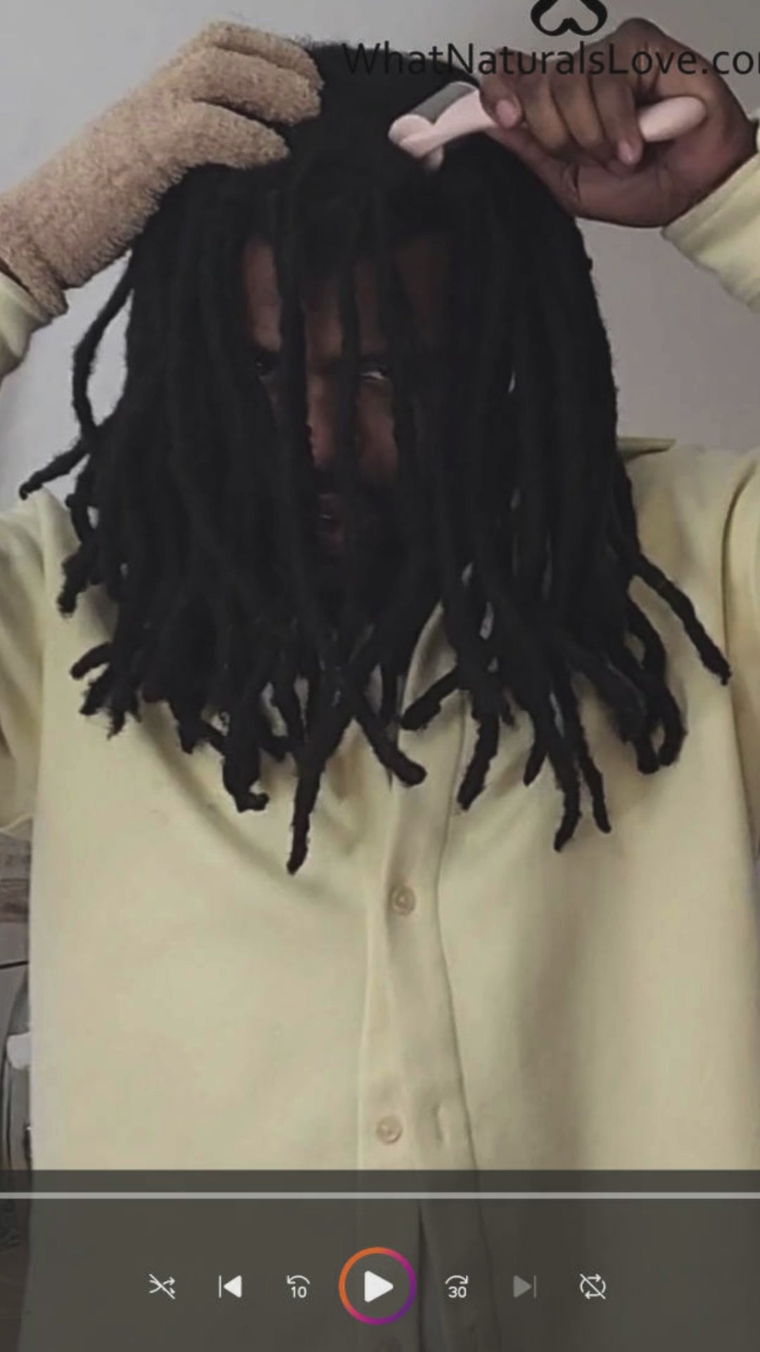 Man with locs using a cryotherapy scalp roller and exfoliating glove to massage his scalp, promoting circulation and reducing itchiness.