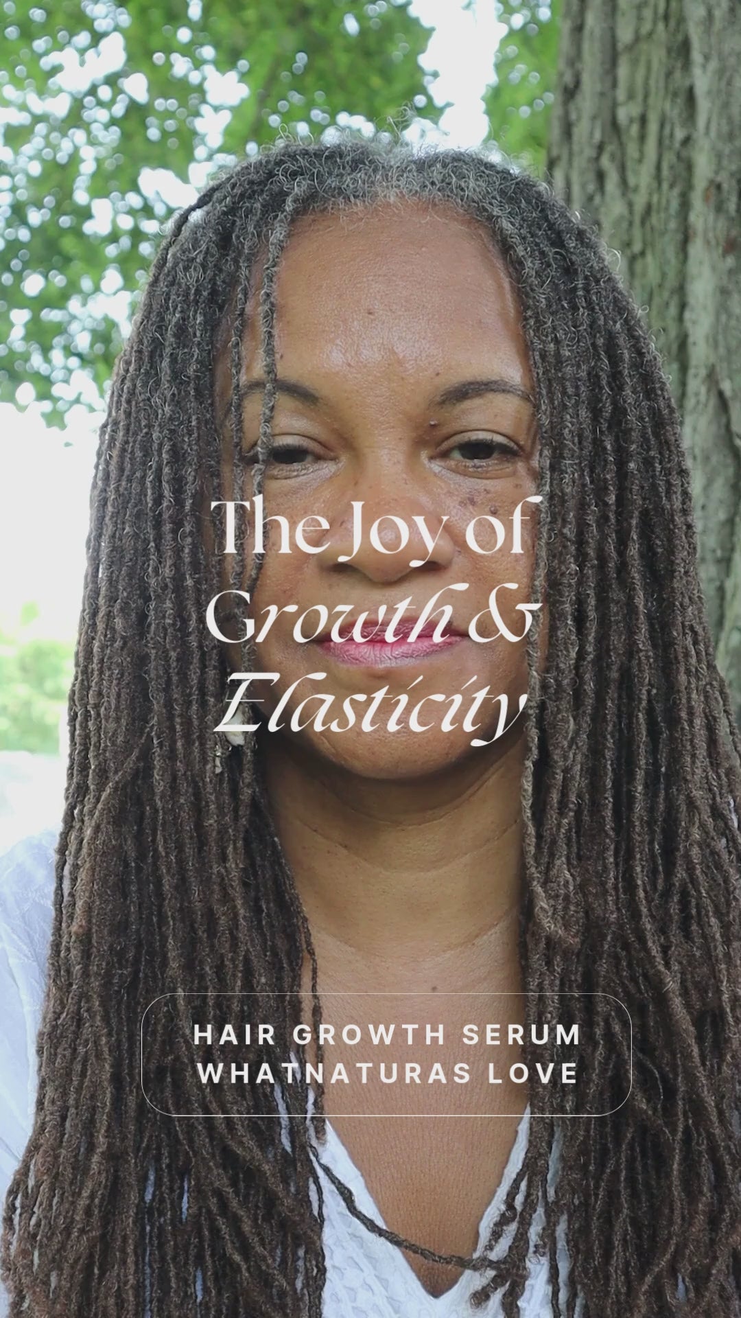 Smiling woman with long, healthy locs promoting What Naturals Love Hair Growth Serum. Natural hair care for hydration and growth.