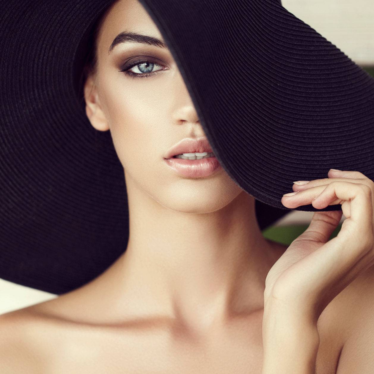 Elegant woman wearing an oversized 27-inch wide brim sun hat in black, perfect for UV protection and summer fashion.