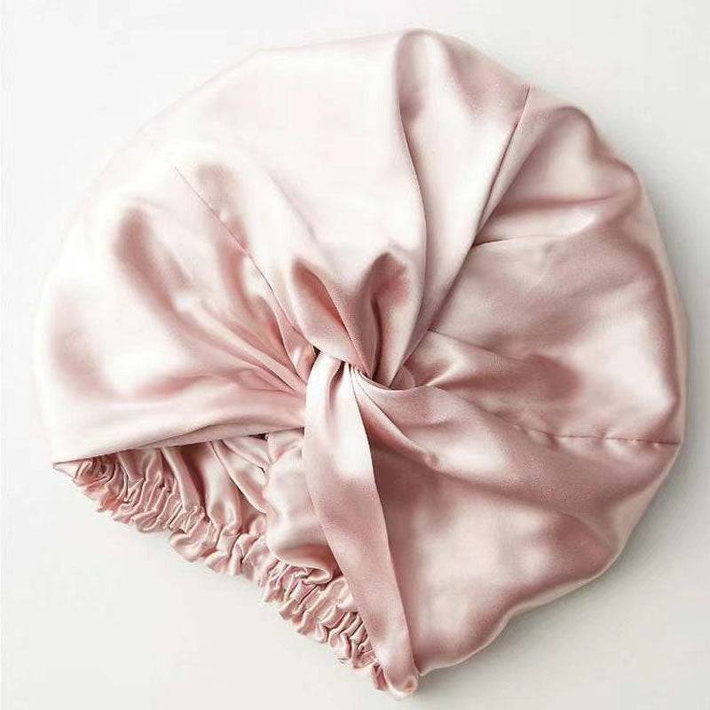 Soft pink Silk Bonnet Amara De Luxe with a twisted front and elastic back. Made from 100% Mulberry Silk for hair protection and comfort.