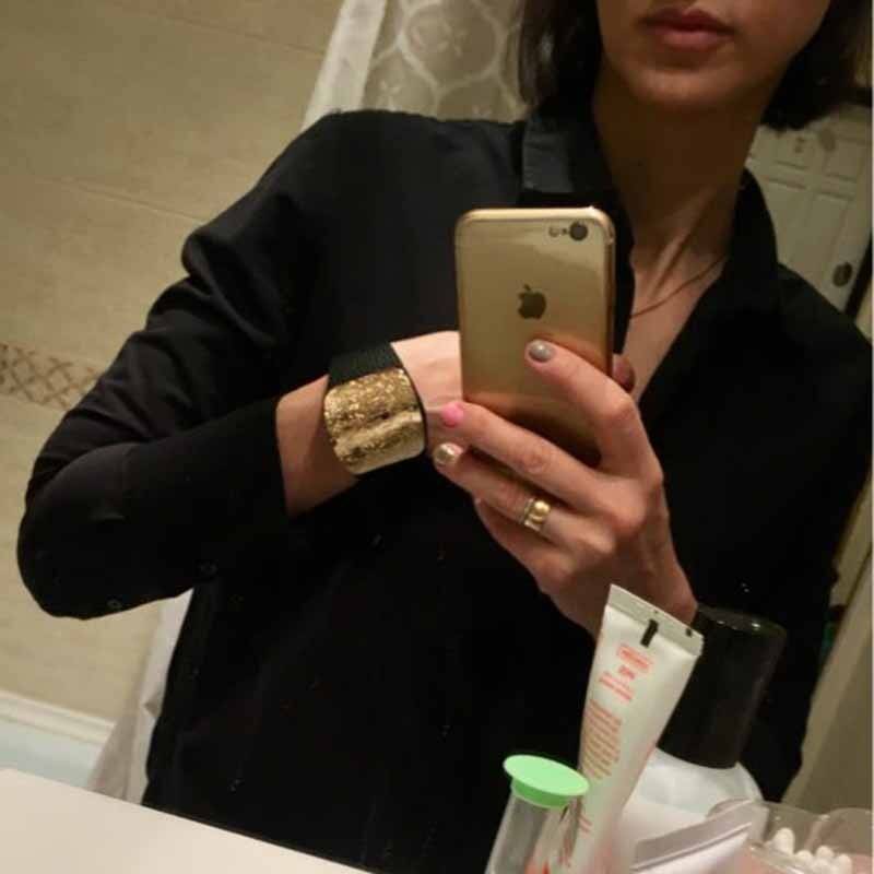 A person wearing a black leather hair cuff with a textured gold plate, showcasing its stylish and elegant design for locs, sisterlocks, and dreadlocks.