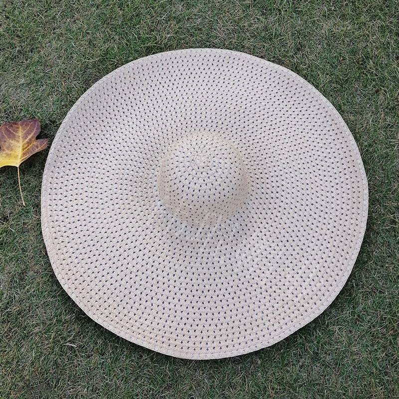 Natural straw oversized 27-inch wide brim sun hat displayed on grass, offering breathable UV protection.
