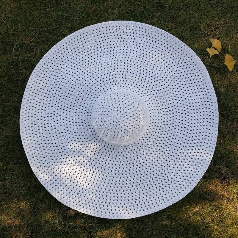 White oversized 27-inch wide brim sun hat placed on grass, ideal for beach vacations and sun safety.