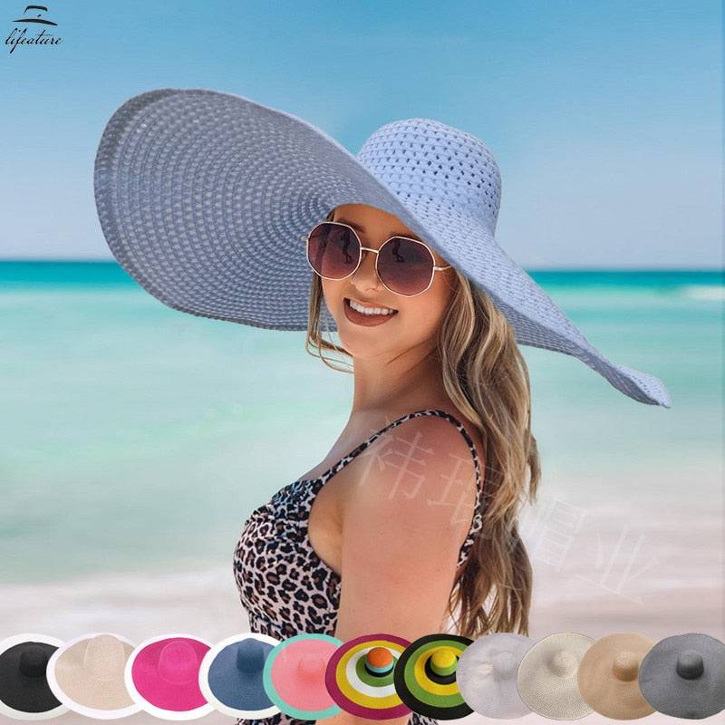 Woman at the beach wearing a white oversized 27-inch wide brim sun hat, available in multiple colors.