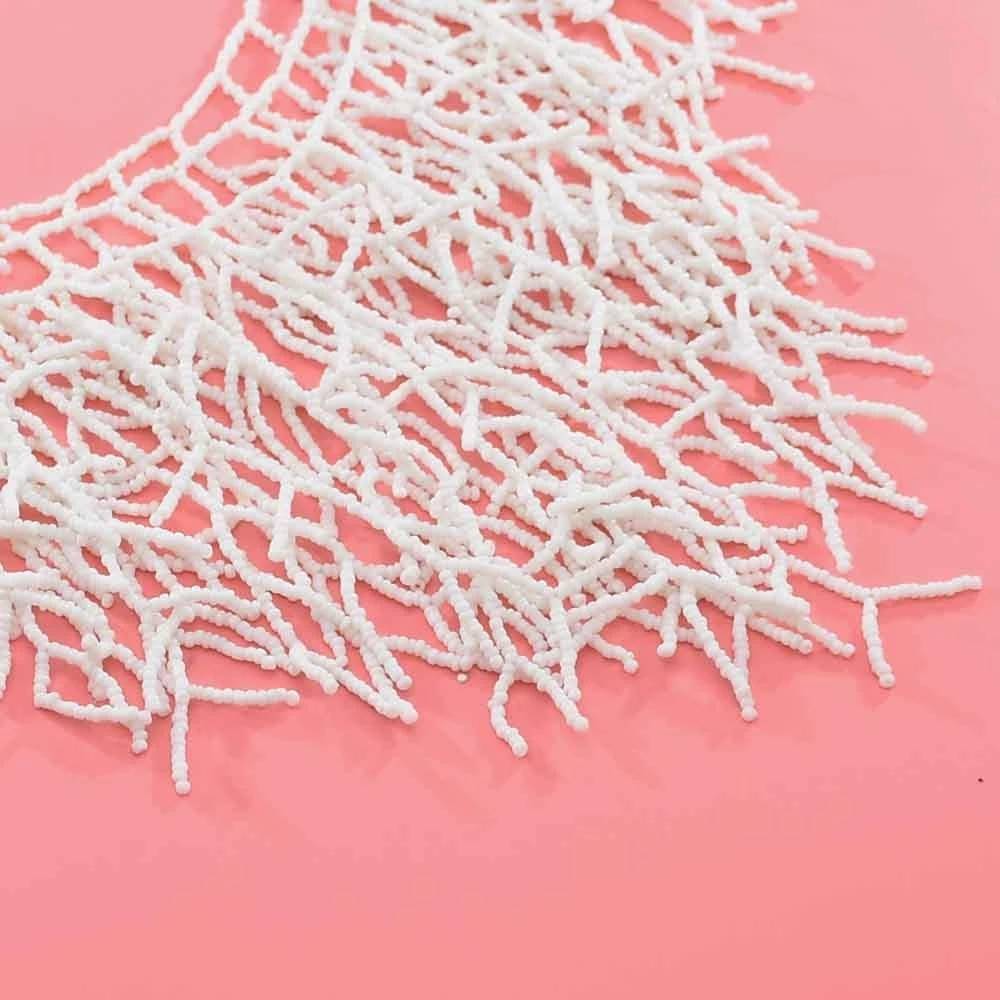 Close-up of a handmade white beaded necklace with intricate coral-inspired details on a pink background. A stunning African necklace for Memorial Day 2024.