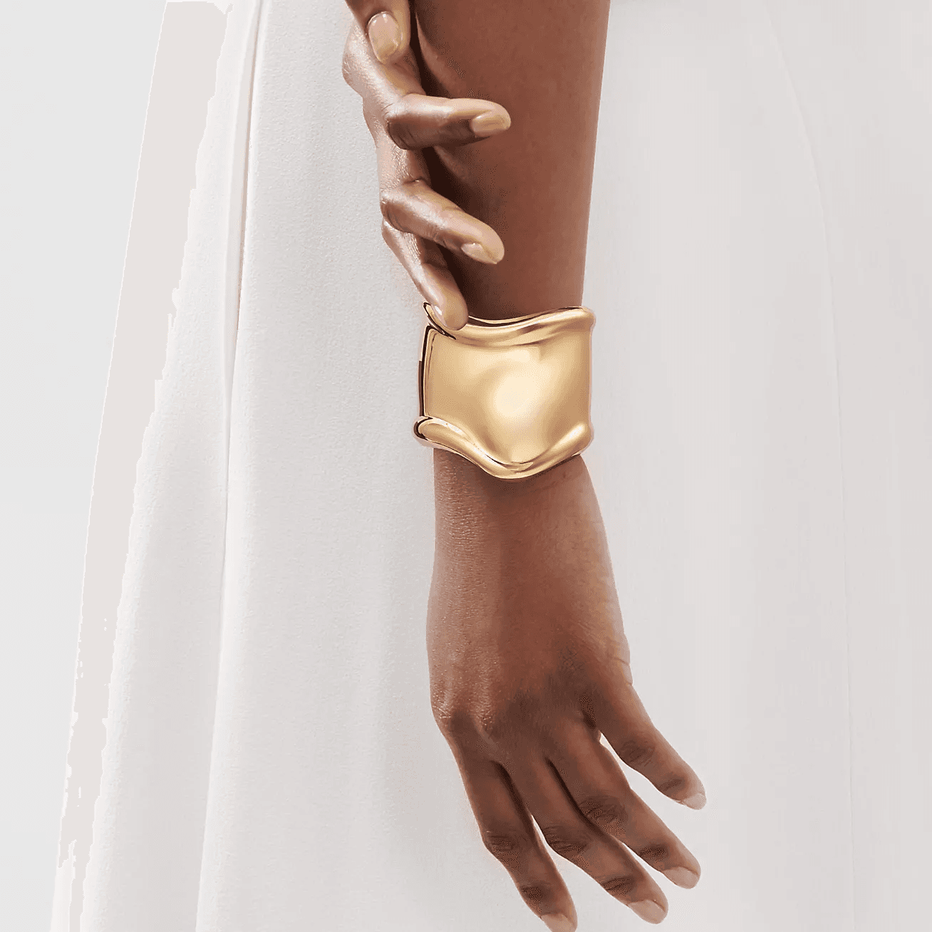 Gold asymmetrical cuff bracelet worn on the wrist. A versatile accessory that doubles as a hair cuff for locs and dreadlocks.
