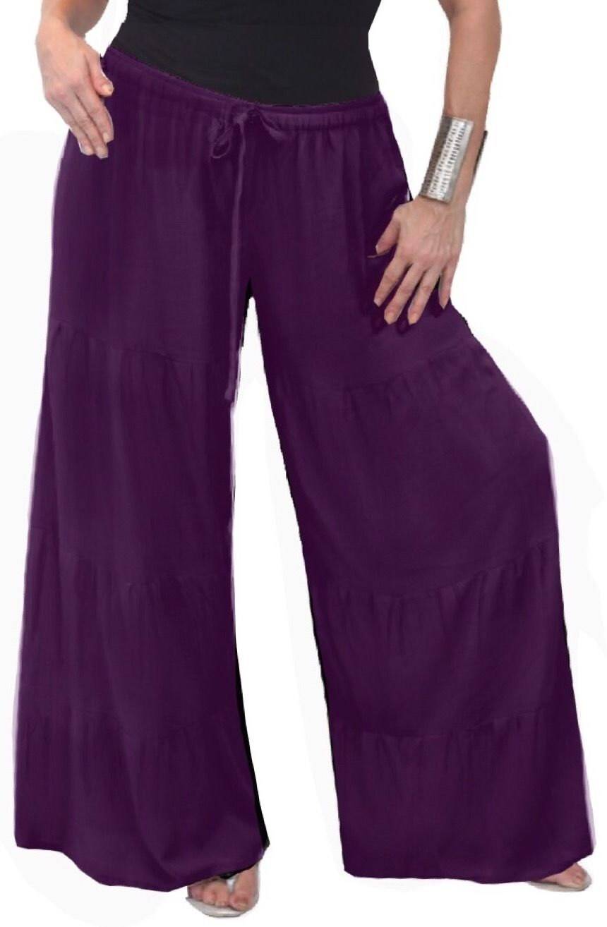 Purple wide-leg pants with ruffled tiers and an elastic waist. Elegant and flowy design for casual or bohemian fashion.