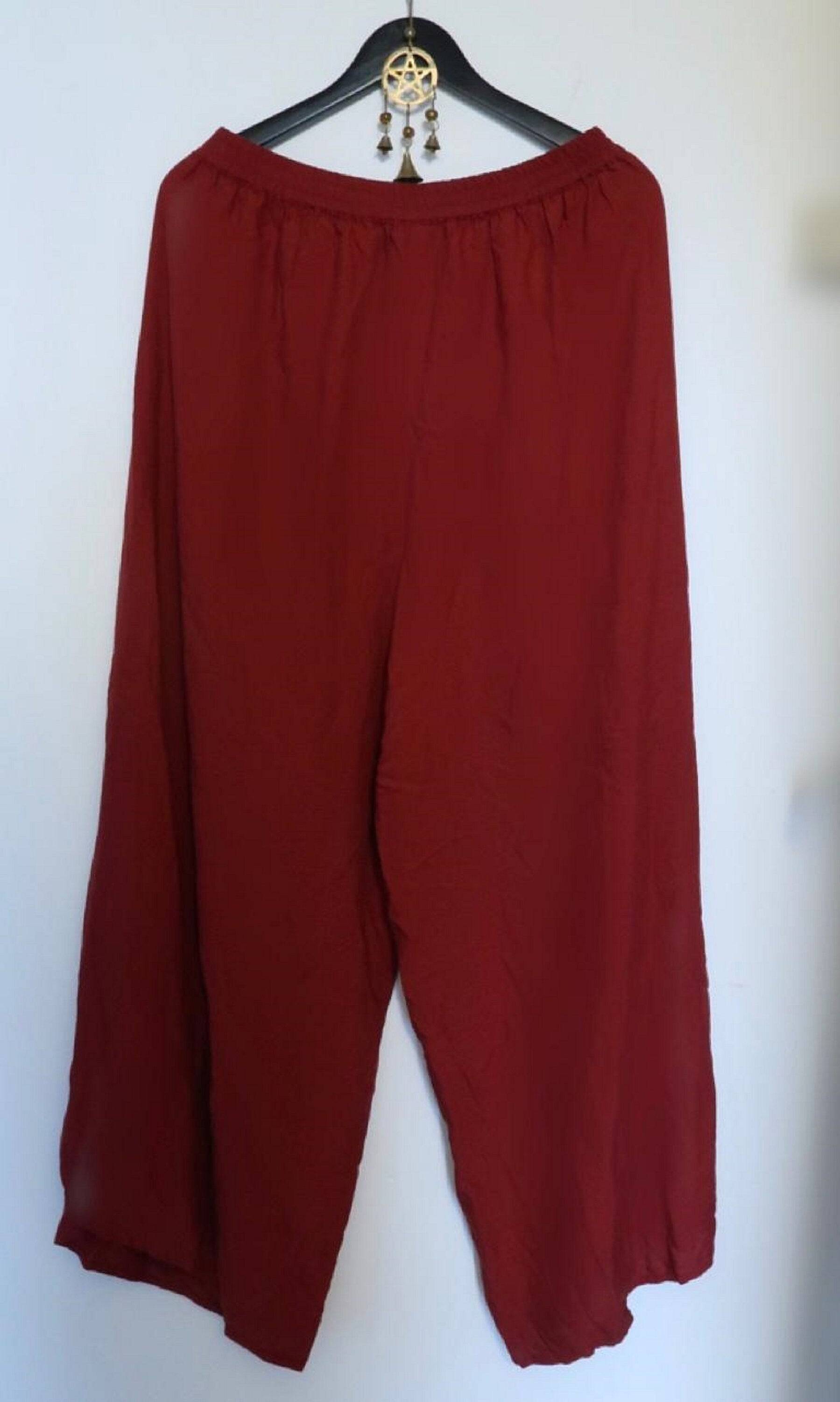 Red faux wrap layered pants with an elastic waist displayed on a hanger. Loose and flowy design for casual and bohemian outfits.