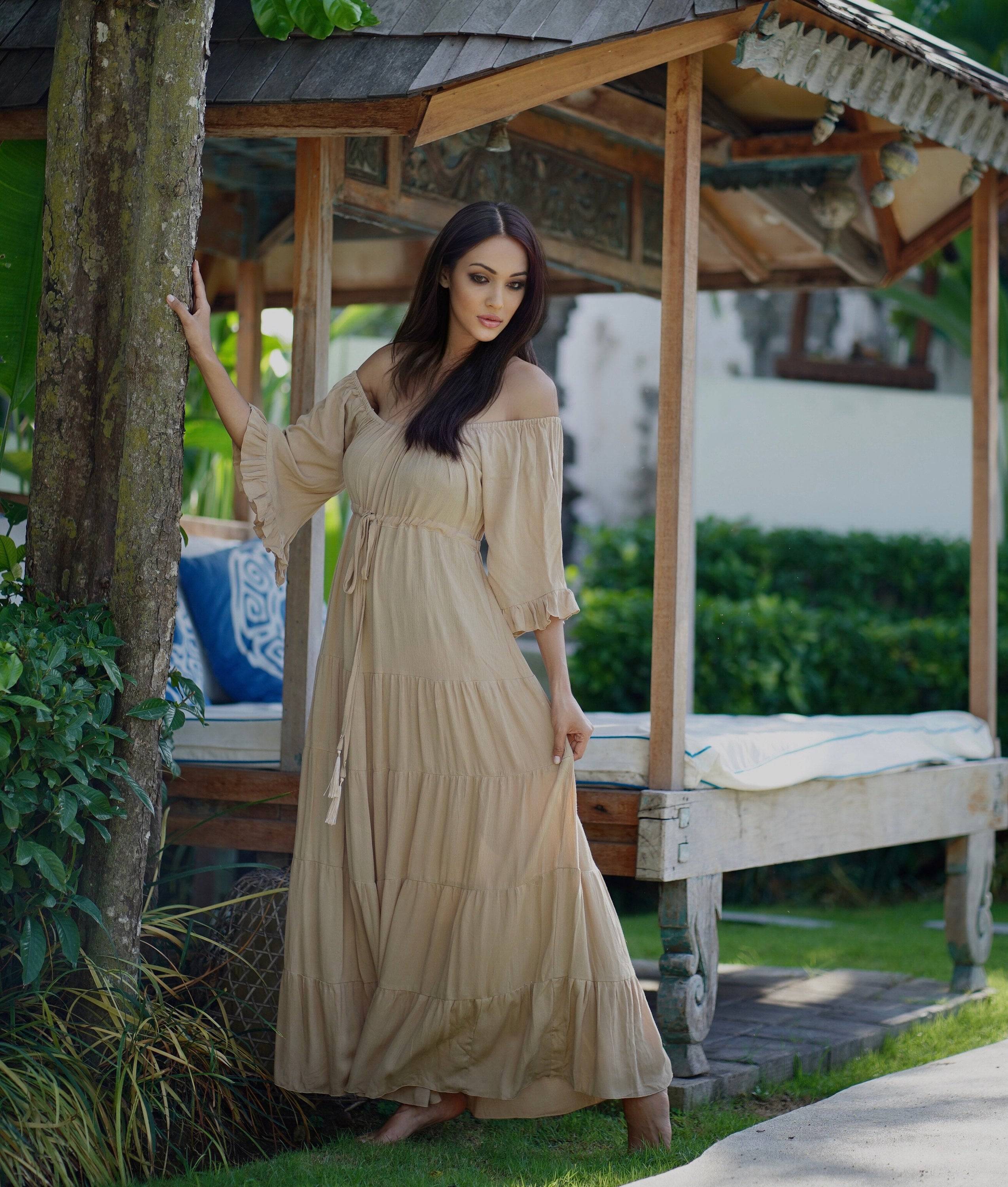 Beige off-shoulder maxi dress with sleeves, styled with a tiered skirt and empire bust. A perfect addition to boho, Viking renaissance, or Wiccan wardrobes.