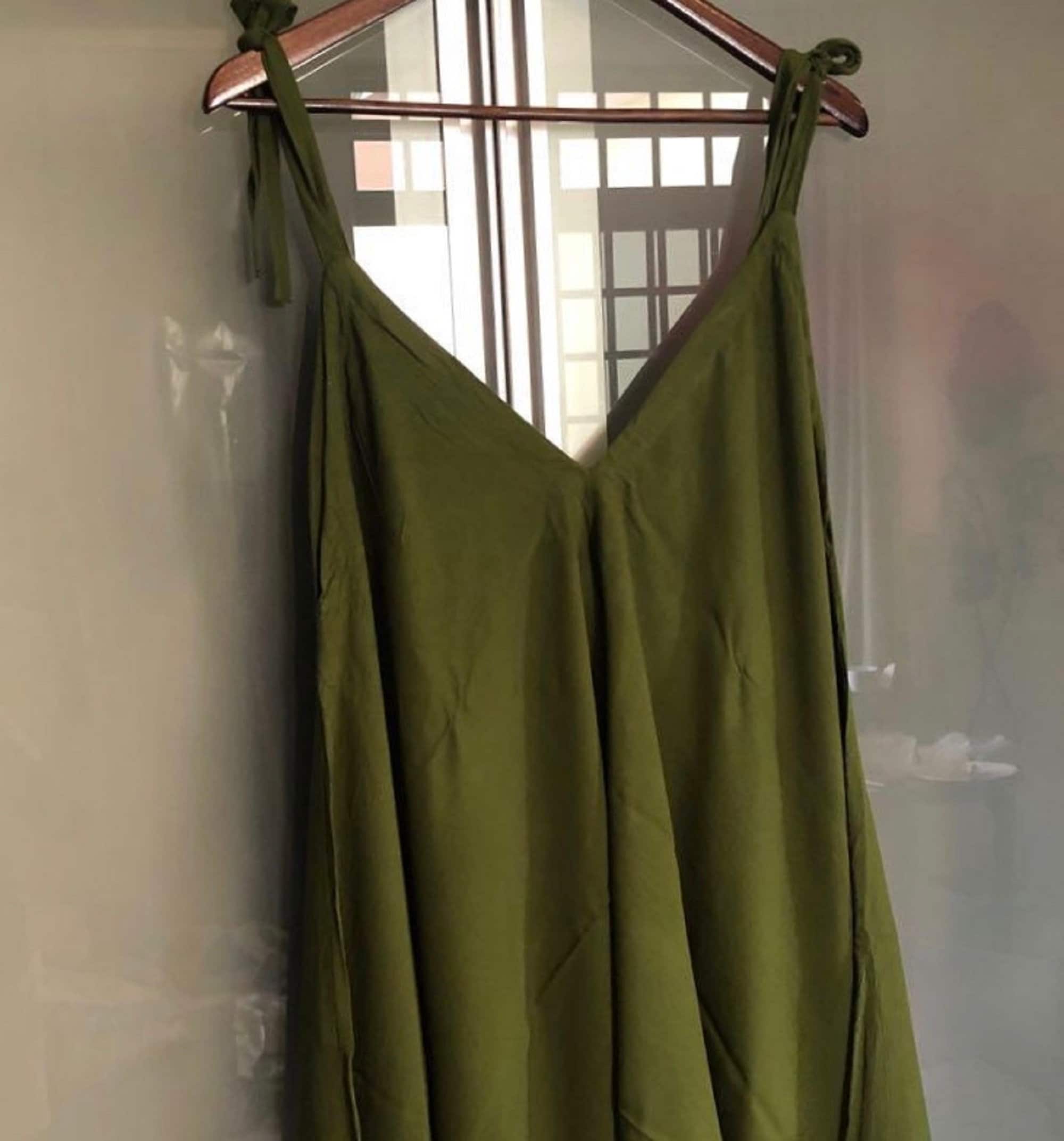 Olive green spaghetti angled straps jumpsuit with loose leg, displayed on a hanger to showcase its soft and flowy fabric.