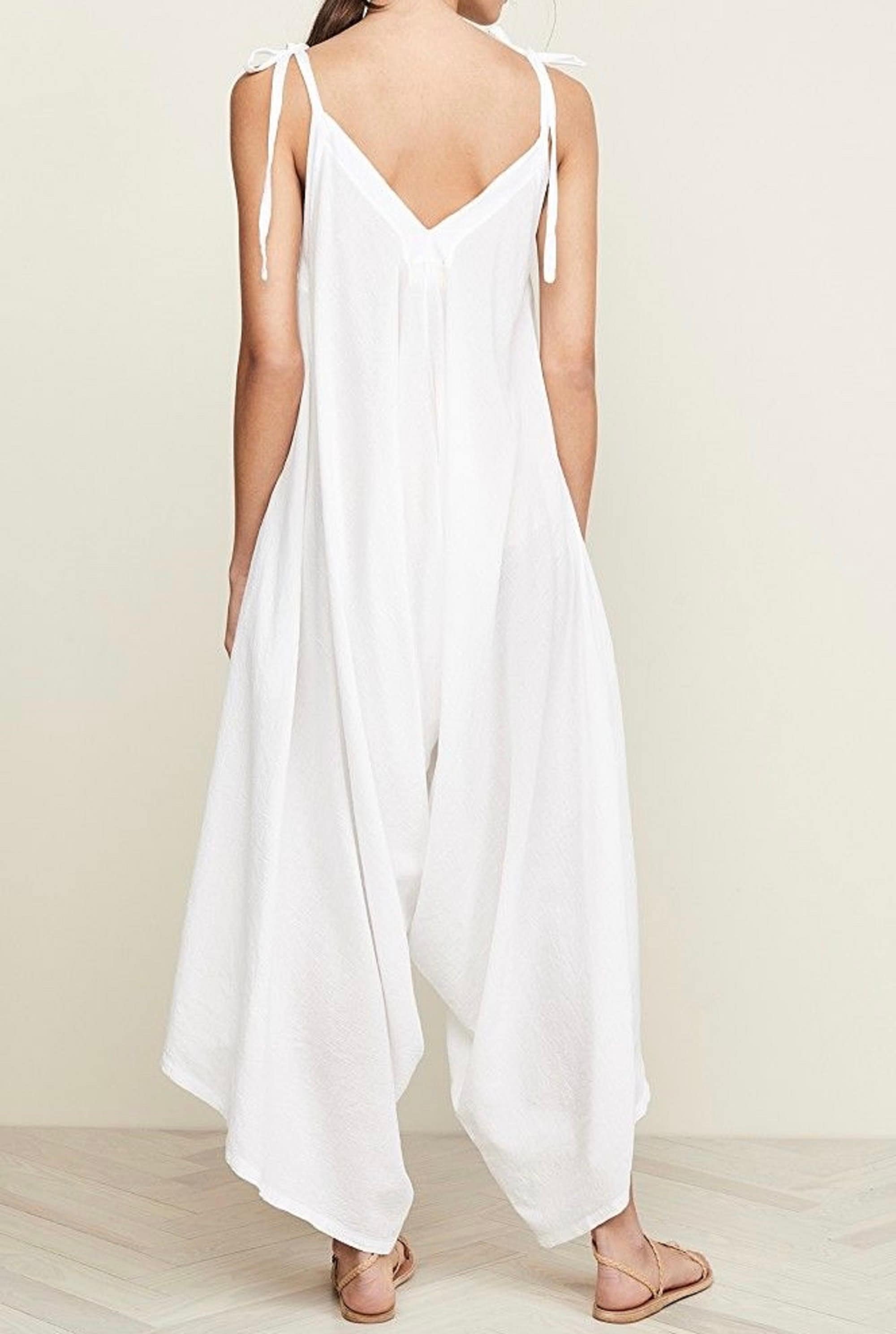Back view of a white spaghetti angled straps jumpsuit with loose leg, showcasing its relaxed fit and flowing fabric.