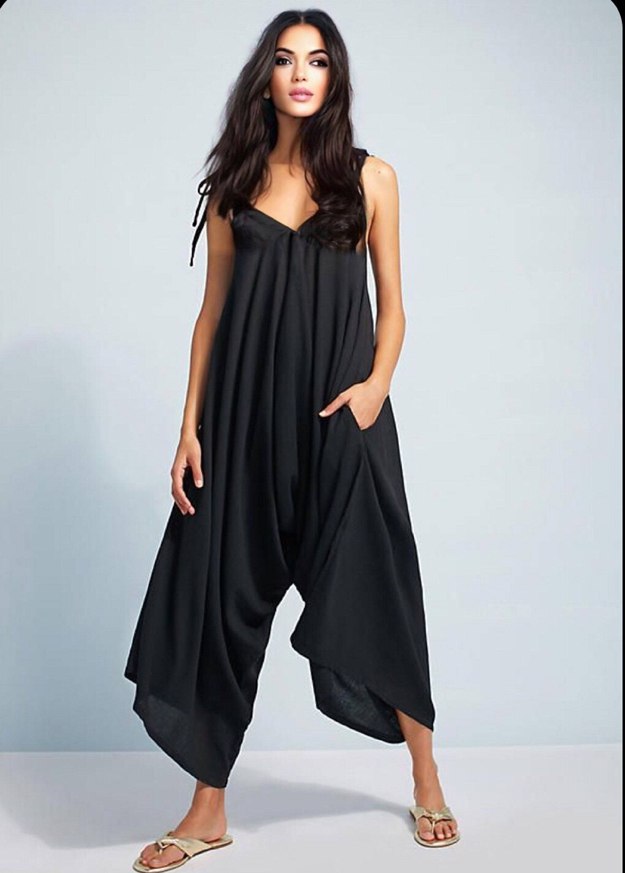 Black spaghetti angled straps jumpsuit with loose leg, styled with flat sandals for a chic and effortless look.