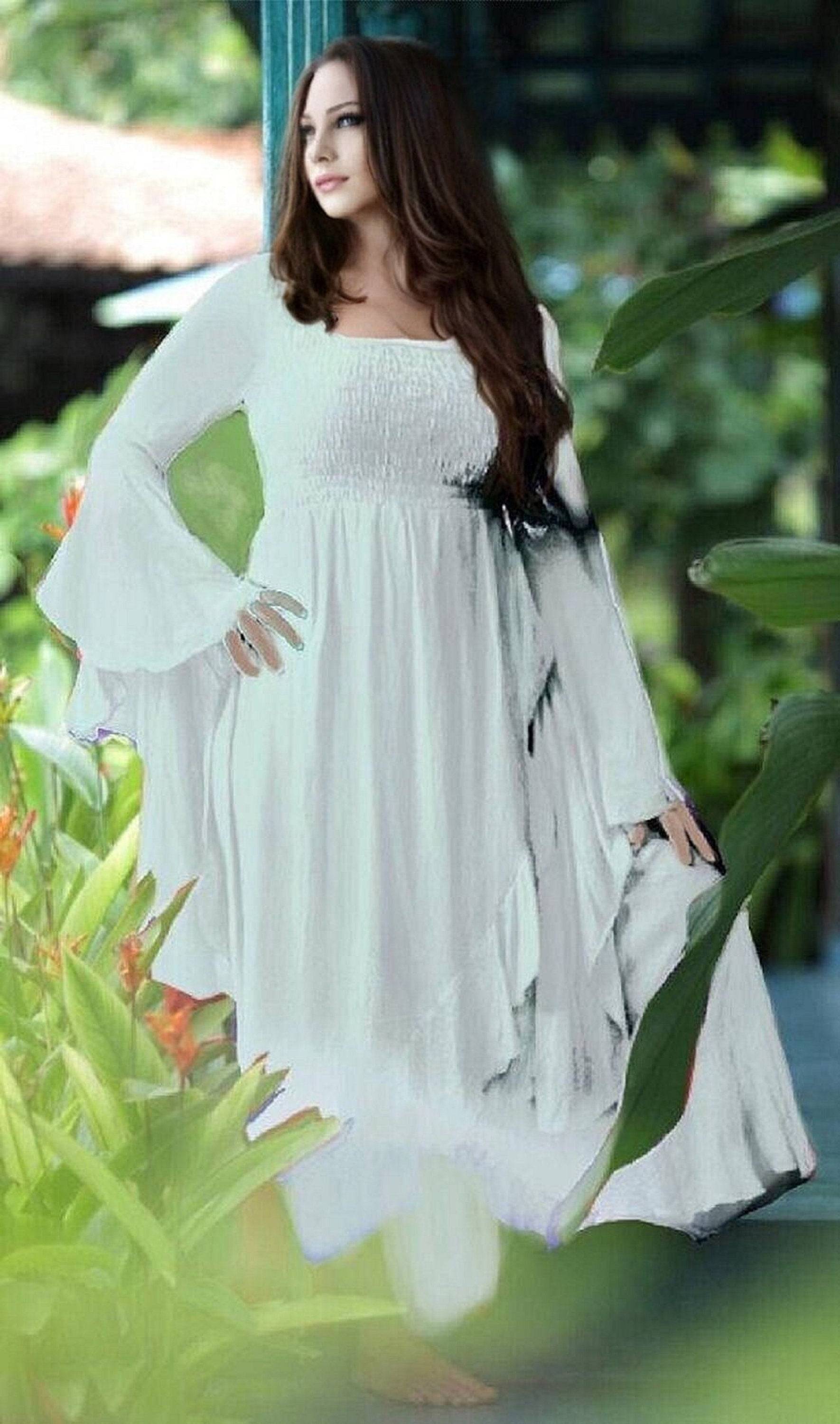 Elegant white ruffle wrap maxi dress with waterfall sleeves, featuring a smocked bodice and flowing silhouette, perfect for boho-chic styling.