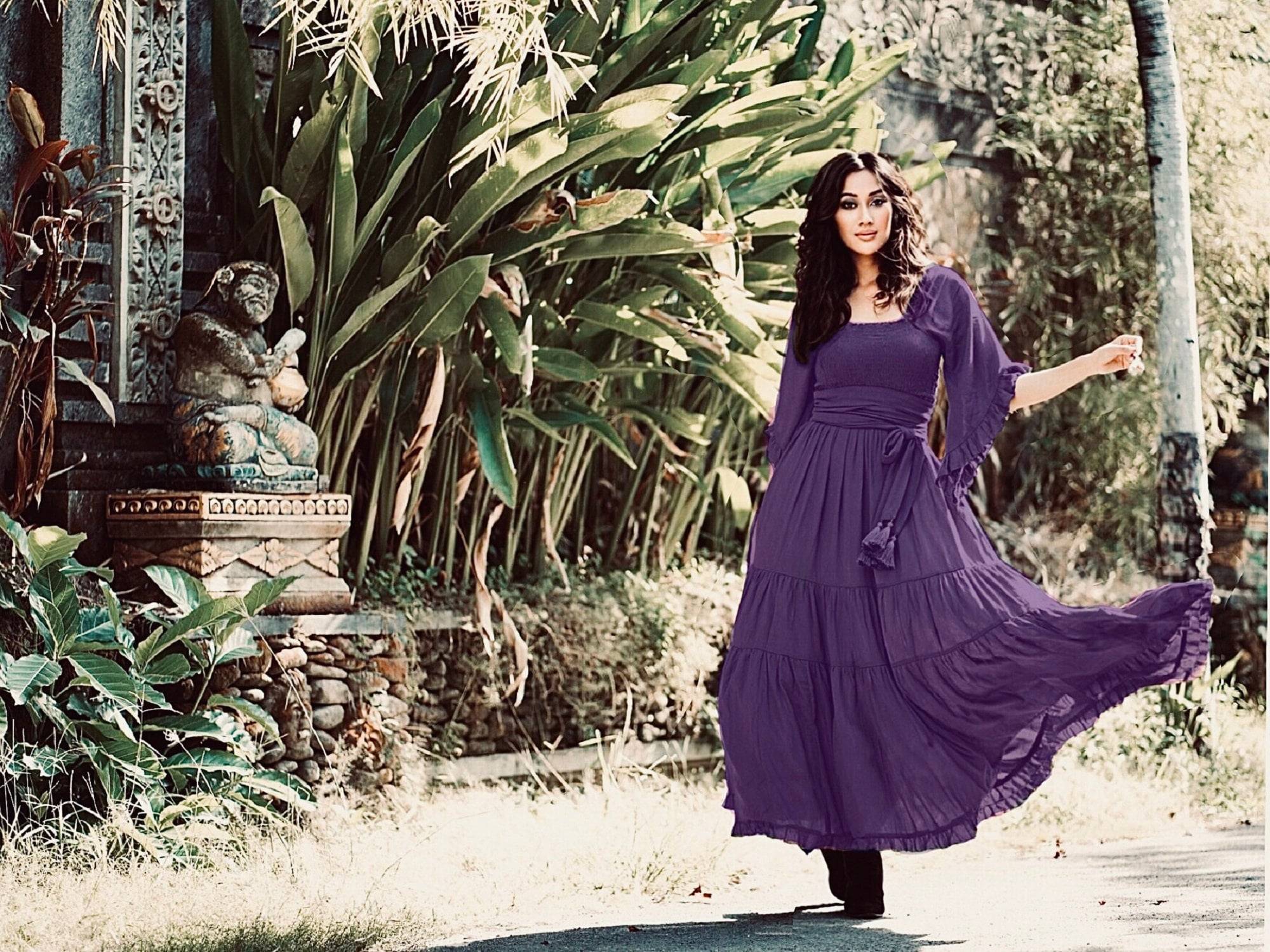 Deep purple medieval vintage maxi dress with an elasticized empire waist and tassel belt, styled in a serene outdoor setting. A perfect blend of elegance and comfort.