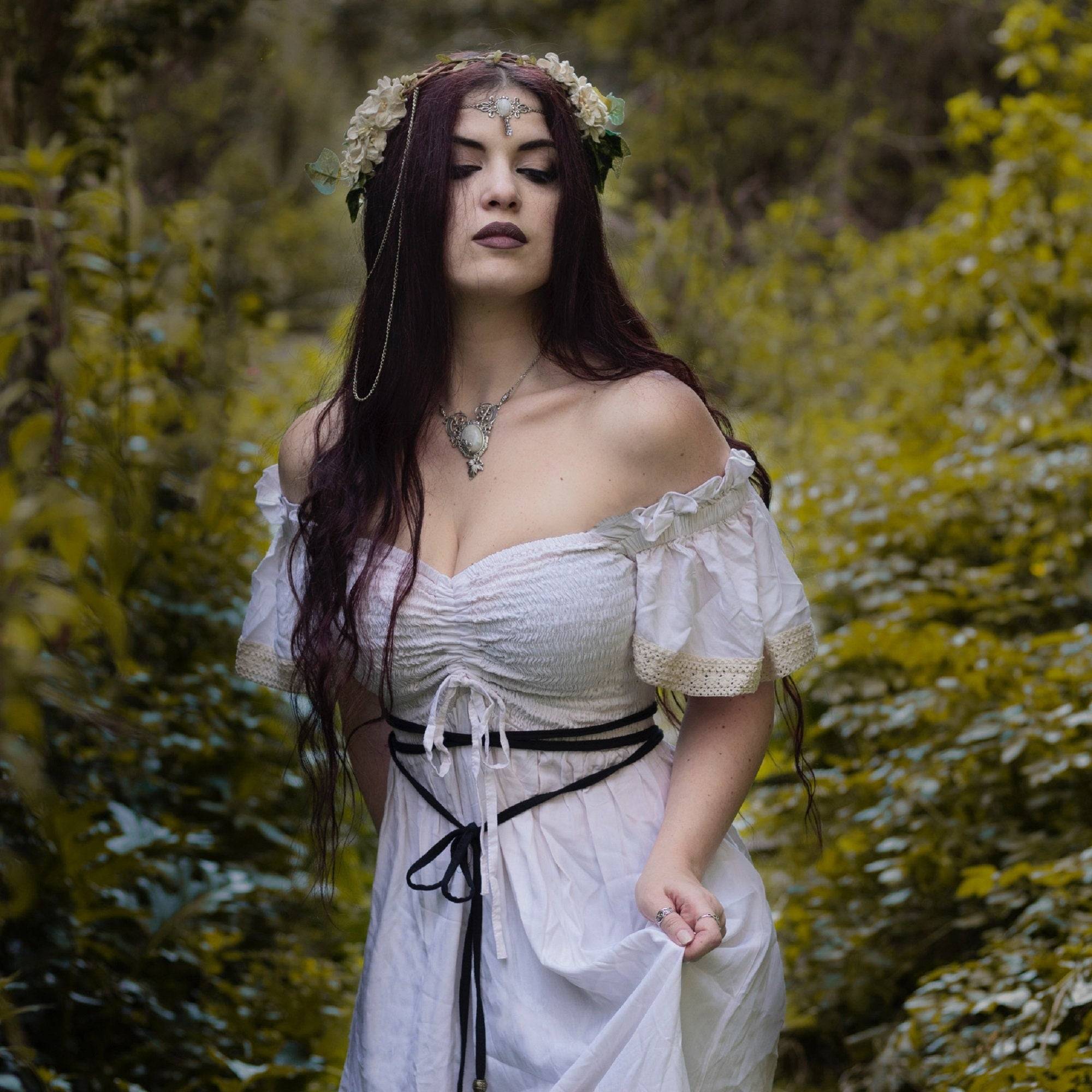 Bohemian white maxi dress with smocked bust and ruffle lace trim, styled with a floral headpiece for a fairy-tale inspired outfit.