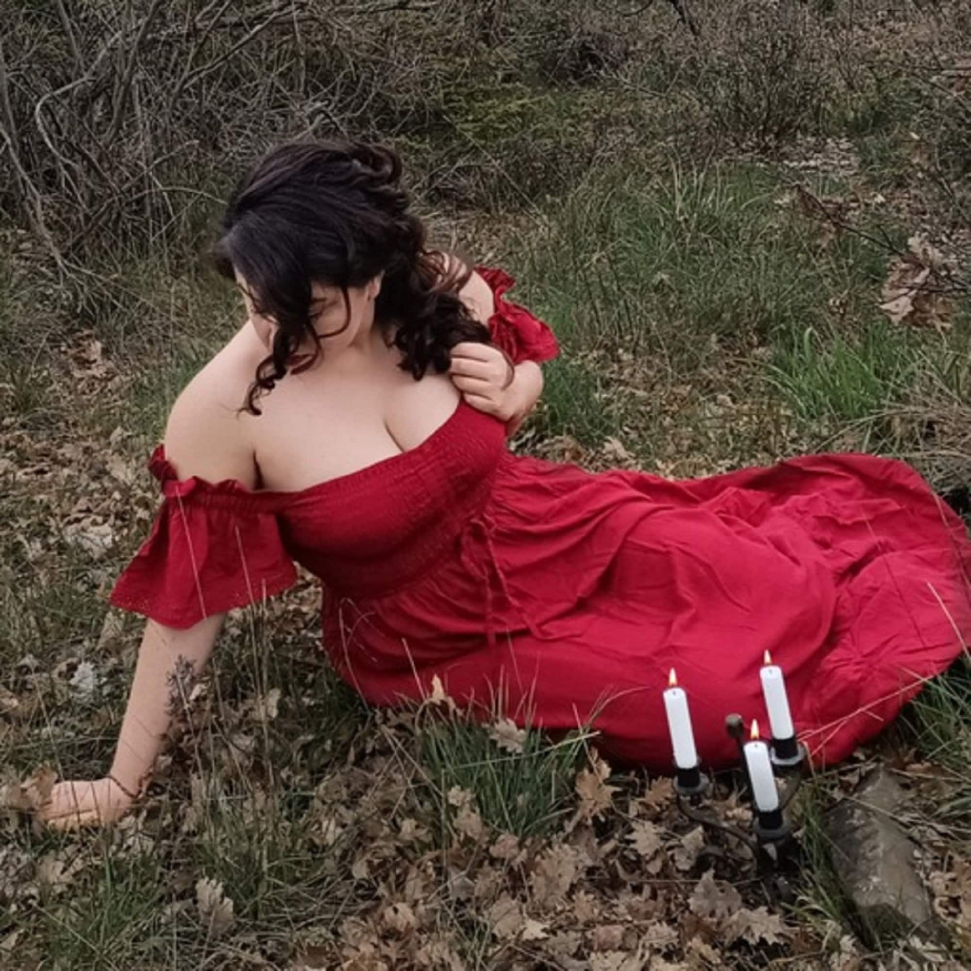 Red off-shoulder maxi dress with smocked bust and ruffle lace trim, worn in a mystical outdoor setting with candlelit ambiance.
