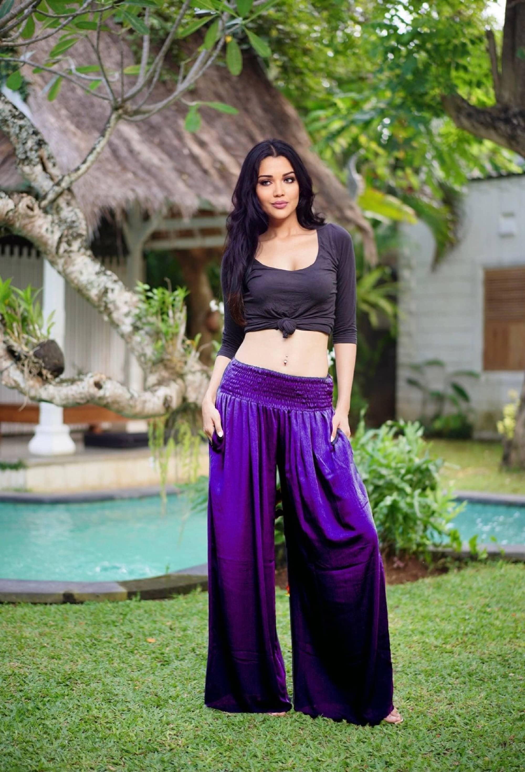 Purple satin wide leg palazzo pants with a smocked waist, adding a luxurious touch to any outfit. Available in sizes S-5X.