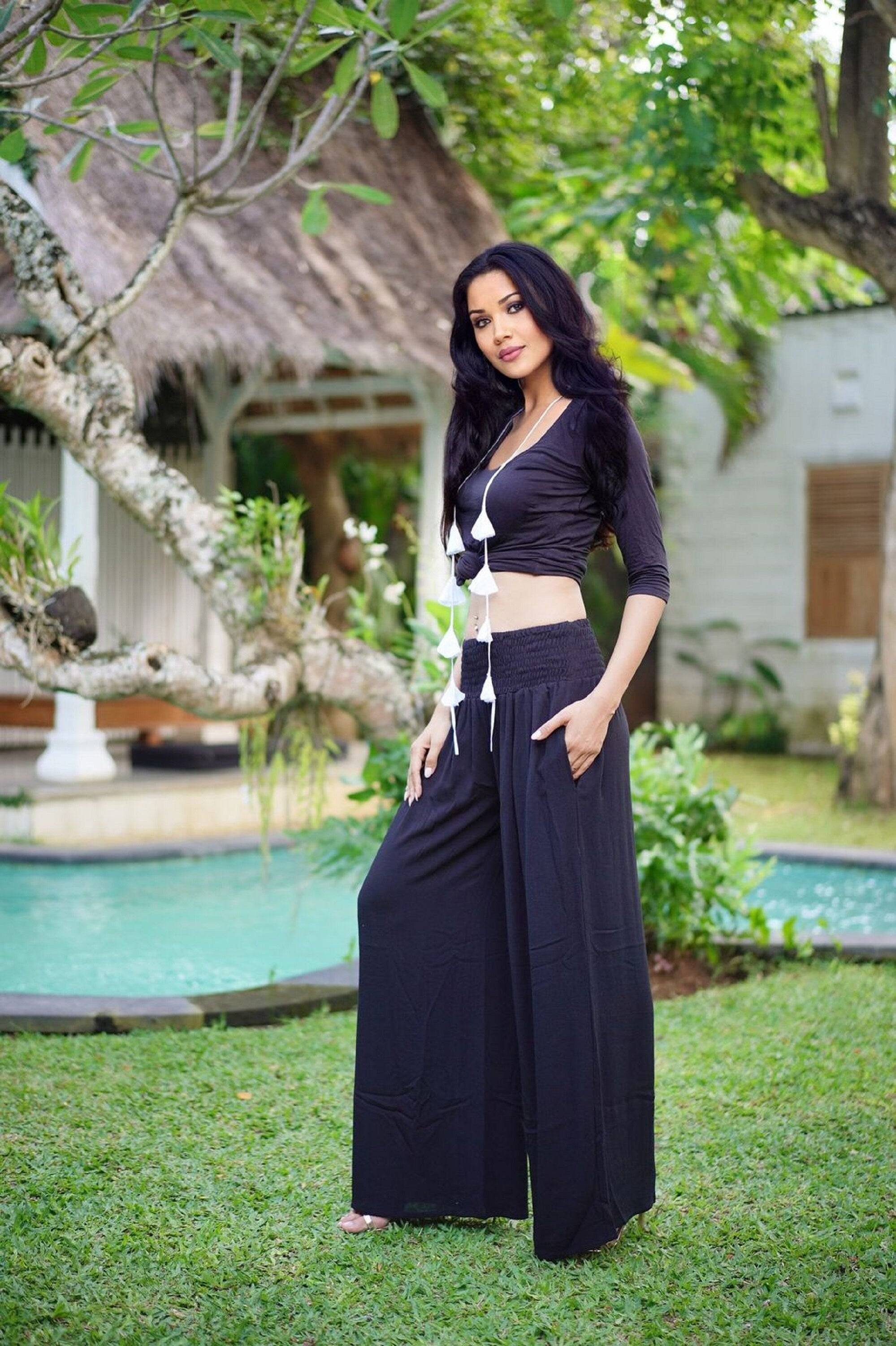 Black wide leg palazzo pants with a smocked waist and side pockets, perfect for comfort and style. Available in all sizes from S to 5X.