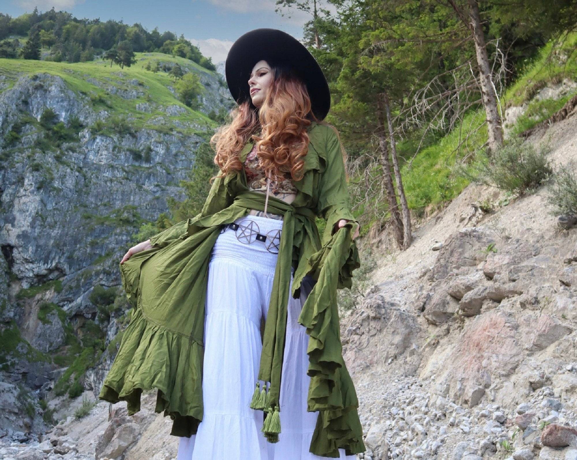Boho kimono-style wrap dress in olive green with ruffle details and a wide wrap belt, worn in a scenic mountain setting.