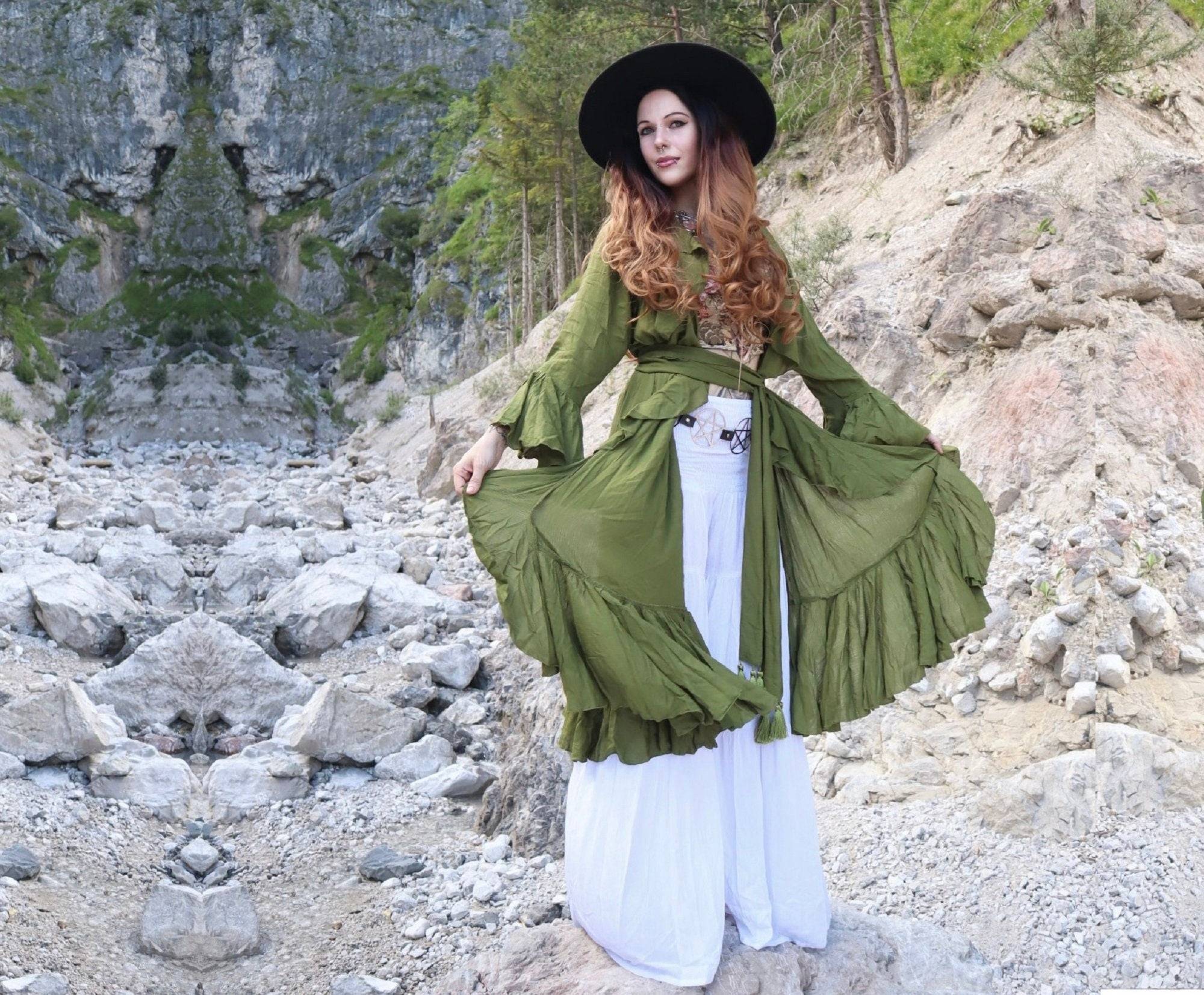 Bohemian-style green kimono wrap dress with ruffle details and a wide belt, styled in a rugged outdoor setting.