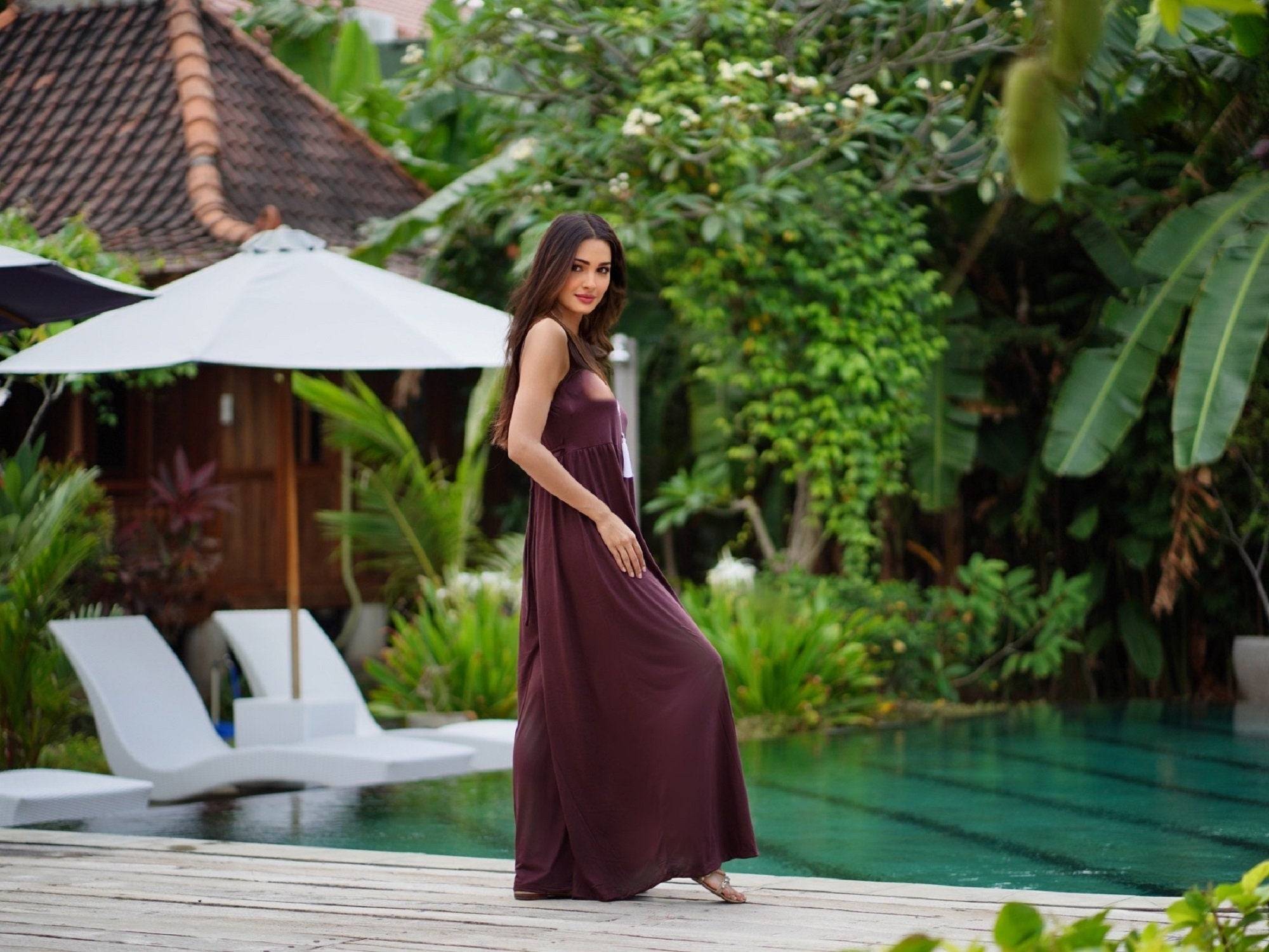 Side view of brown jersey jumpsuit with a flowy palazzo leg design and empire waist. Ideal for casual and elegant occasions, S-5X.