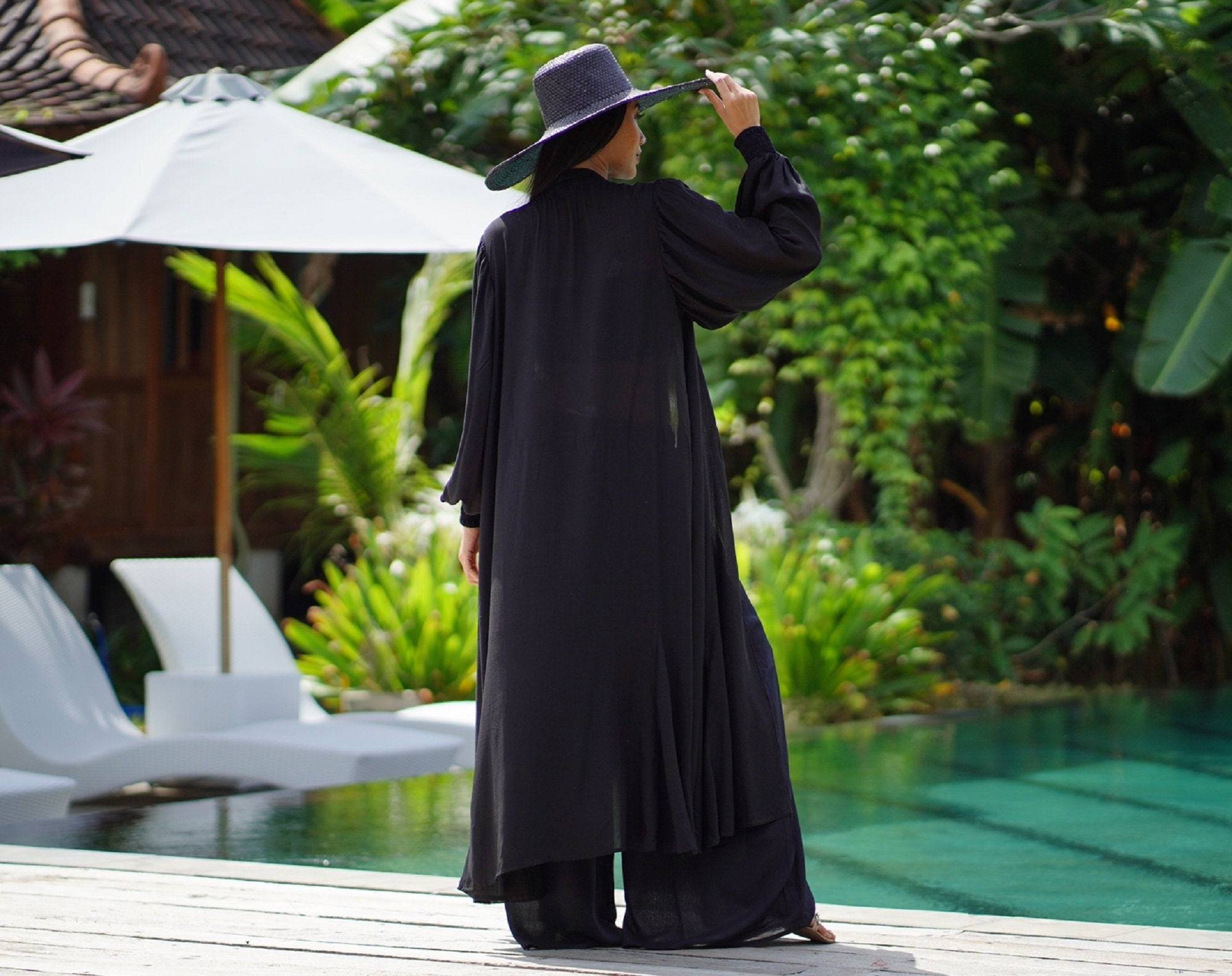 Back view of a black three-piece outfit with a long kimono jacket, elasticized crop top, and palazzo pants, showcasing its elegant drape.