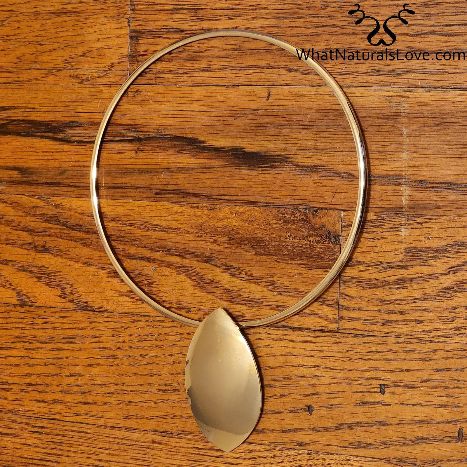 Outstanding Oval choker necklace in gold displayed on a wooden surface. A stylish and sophisticated jewelry piece for Memorial Day 2024.