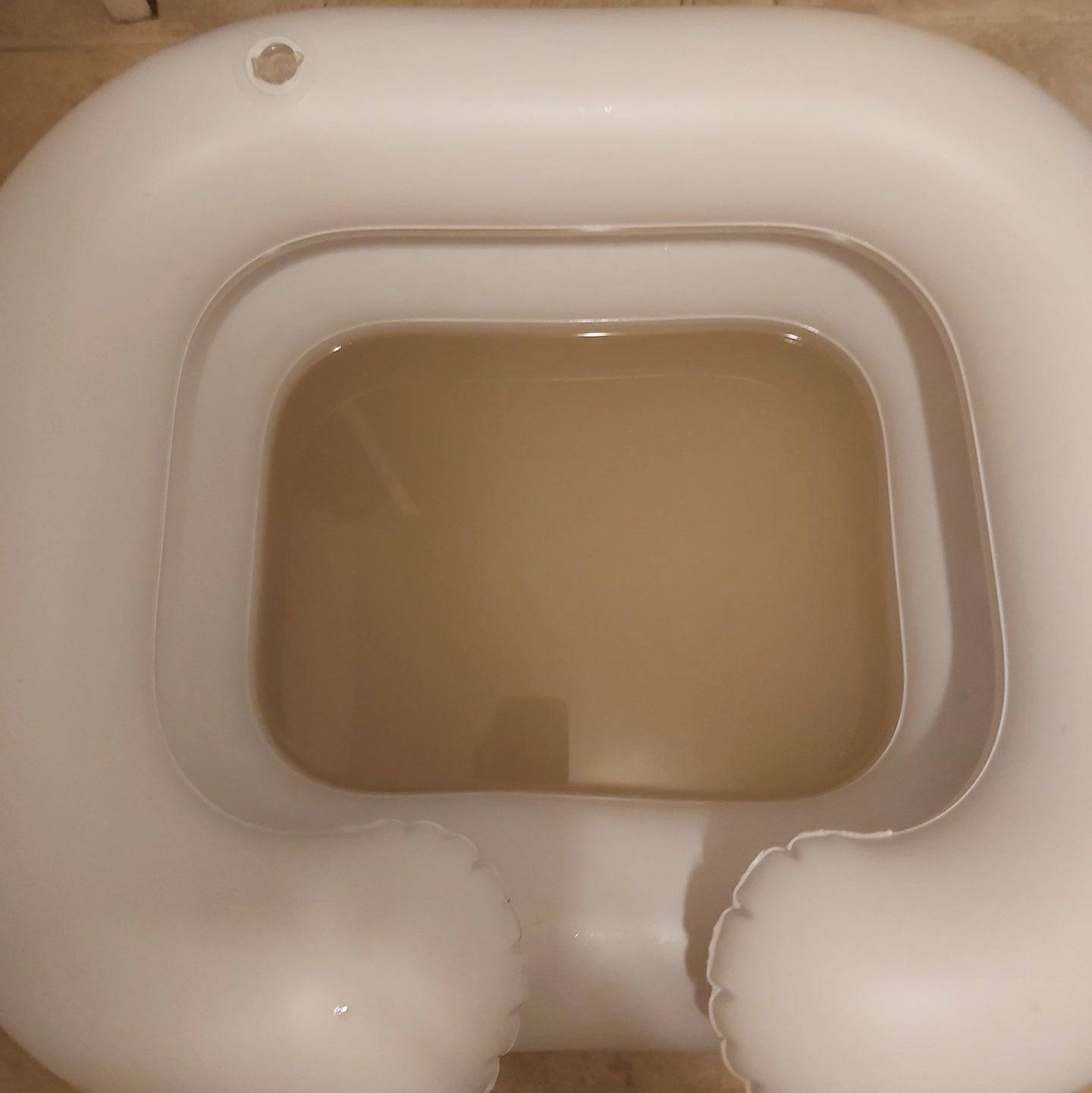 Inflatable basin filled with murky water after using the Sonic Loc Detox Rod, showing removed buildup from locs.