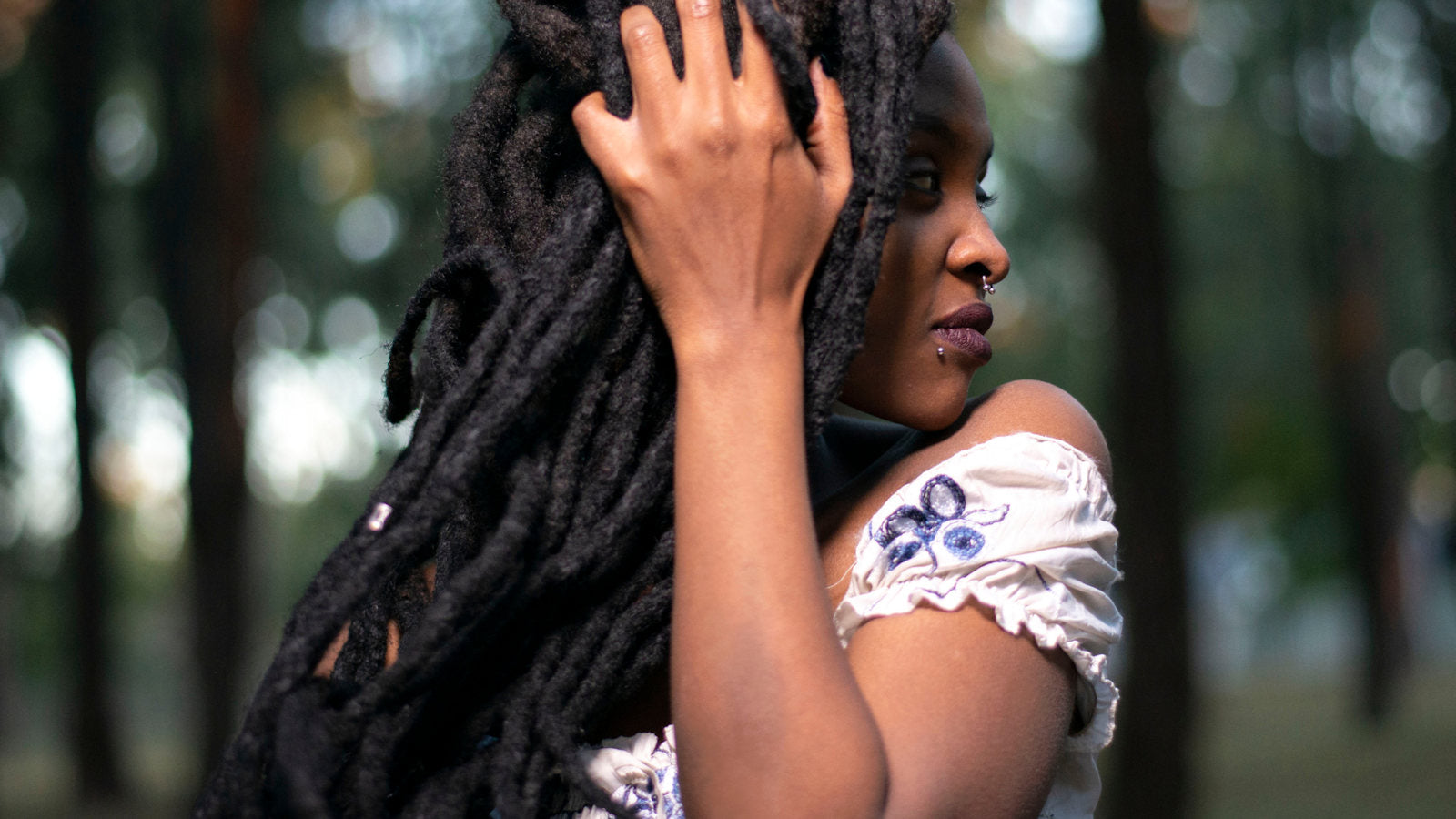 A Woman with Long thick Dreadlocks with Loc Jewelry Wearing a white cotton dress