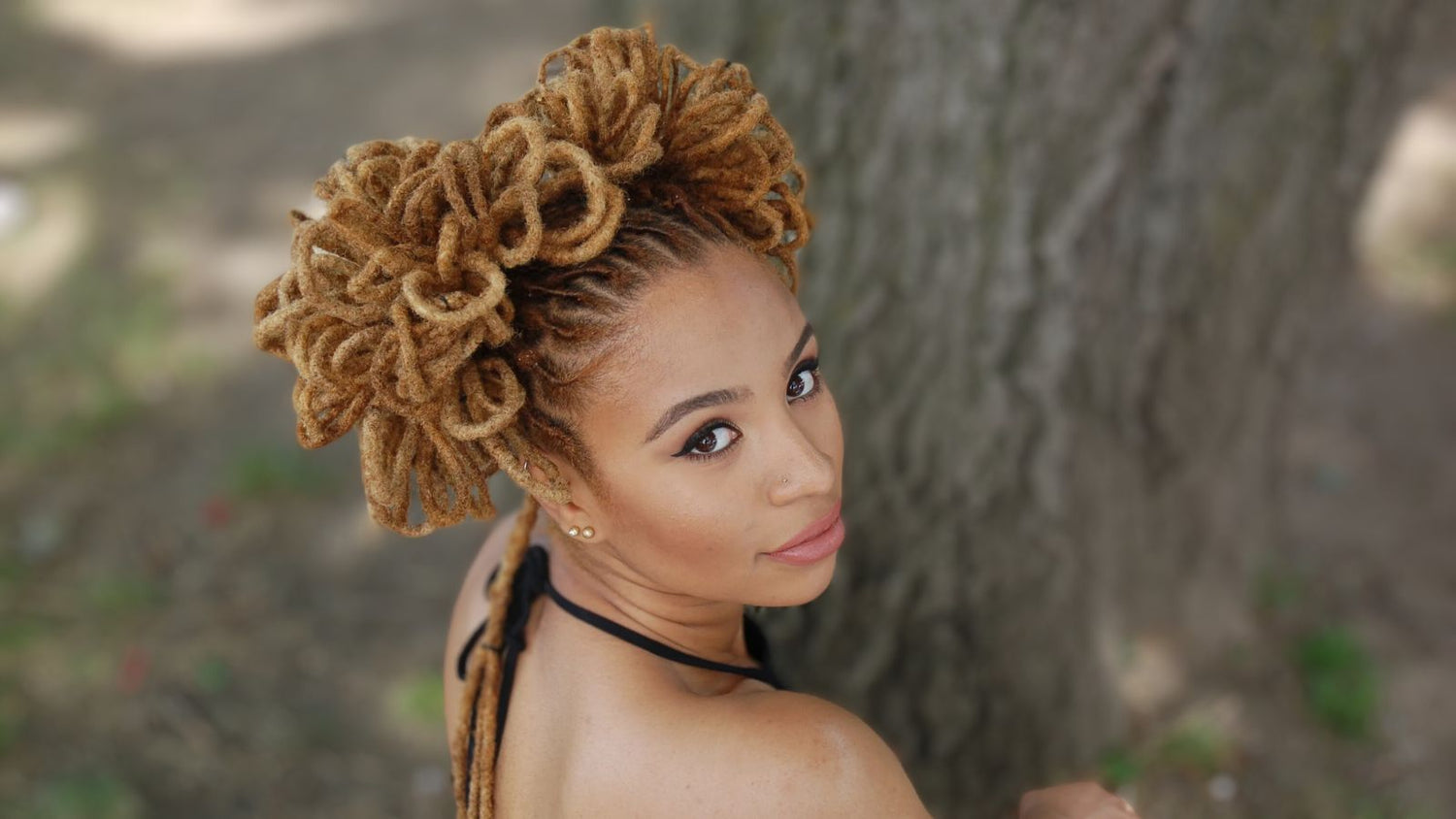 A woman with long mature Dreadlocks style her hair in Petal Rose Loc Buns