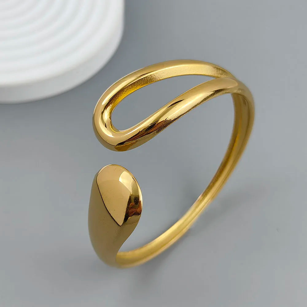 Adjustable gold-plated cuff ring with modern minimalist open loop design on a gray background