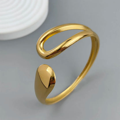 Adjustable gold-plated cuff ring with modern minimalist open loop design on a gray background